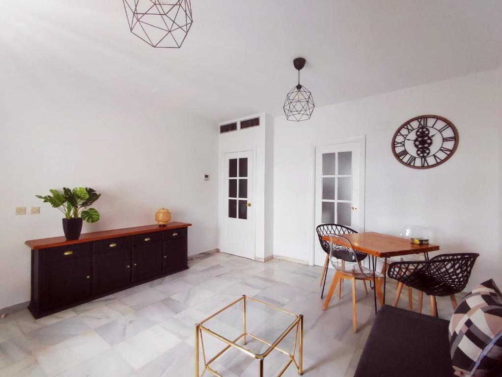 a living room with a table and chairs and a clock at Florencio Quintero Home in Seville