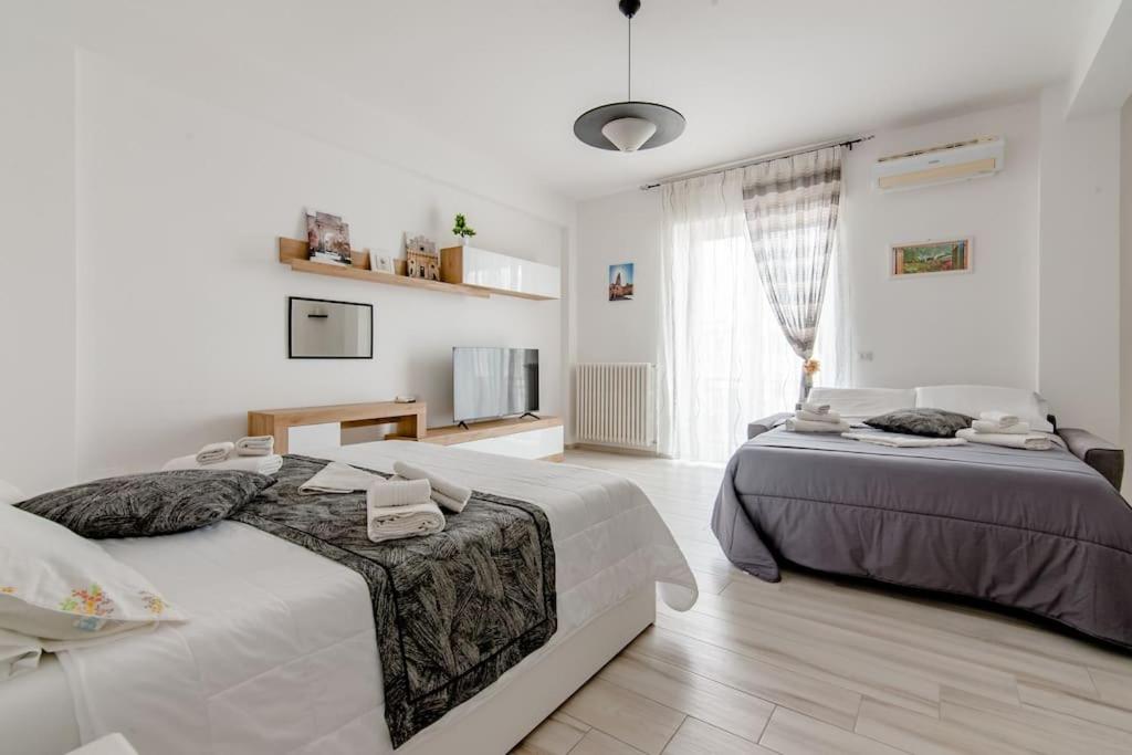 een witte slaapkamer met 2 bedden en een televisie bij Il Barone Rosso B&B in Lecce