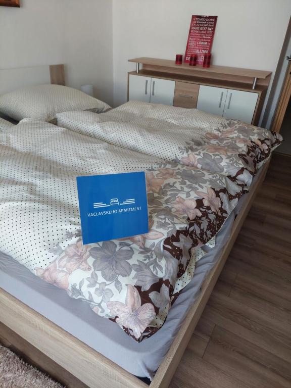 a bed with a blue sign on top of it at Vaclavskeho Apartment Medzilaborce in Medzilaborce