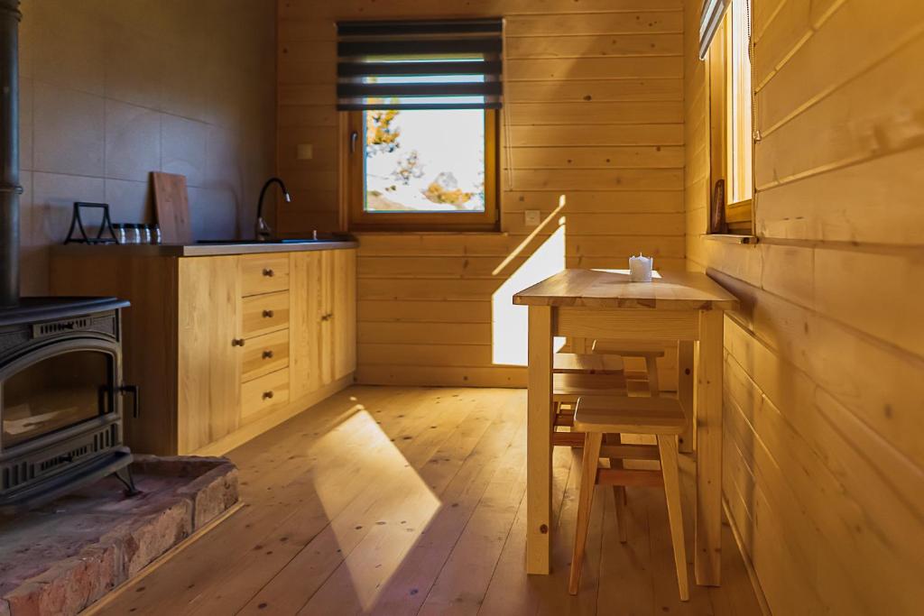 Sunlit wooden kitchenette with stove, sink, drawers and small dining table casting warm light.