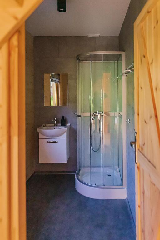 Compact bathroom with glass corner shower, wall-mounted sink, mirror and minimal neutral tiles.