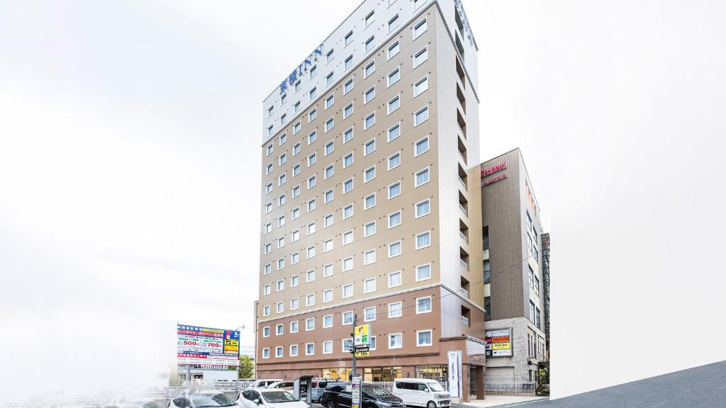 una representación de un hotel con coches estacionados frente a él en Toyoko Inn Kita-asaka-eki Nishi-guchi en Asaka