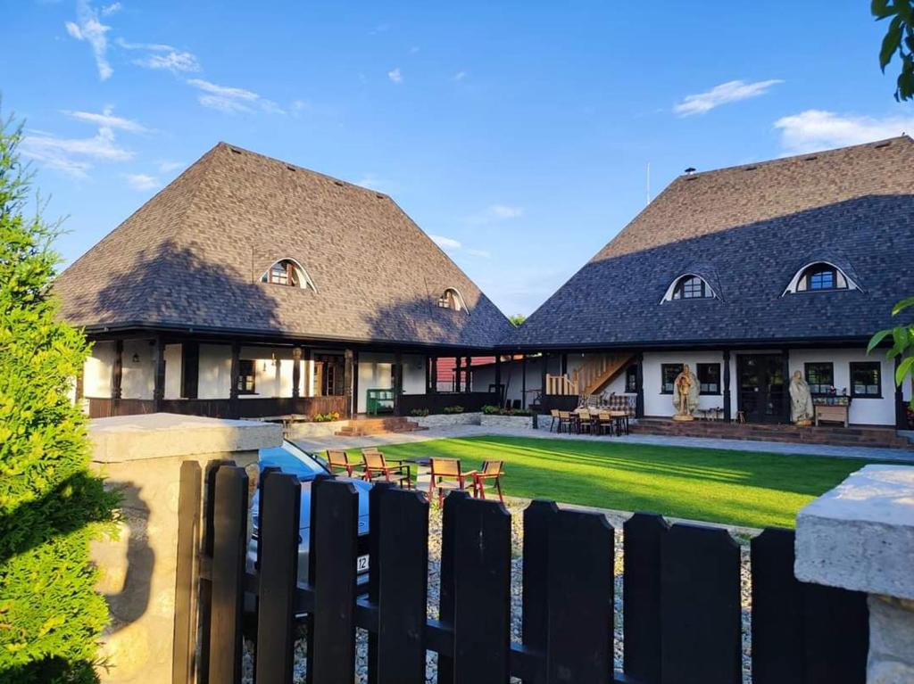 une maison avec un toit de chaume et une clôture dans l'établissement Ograda Bunicilor, à Baia de Fier