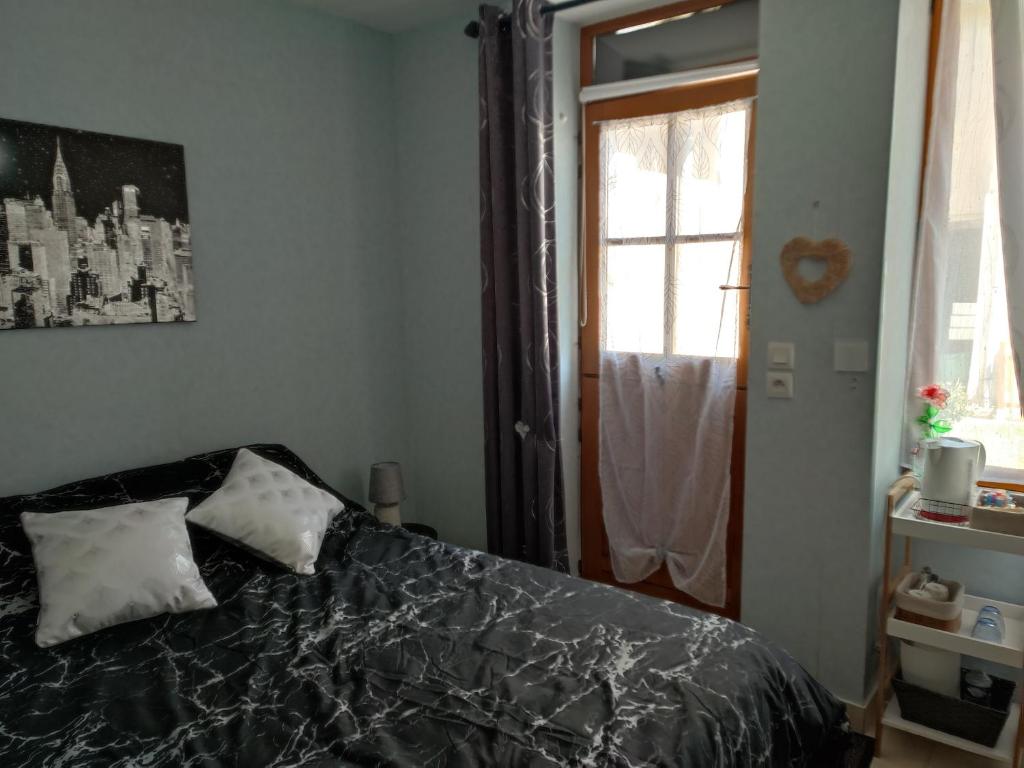 1 dormitorio con 1 cama con manta negra y ventana en Chambre d hote, en Bonnétable