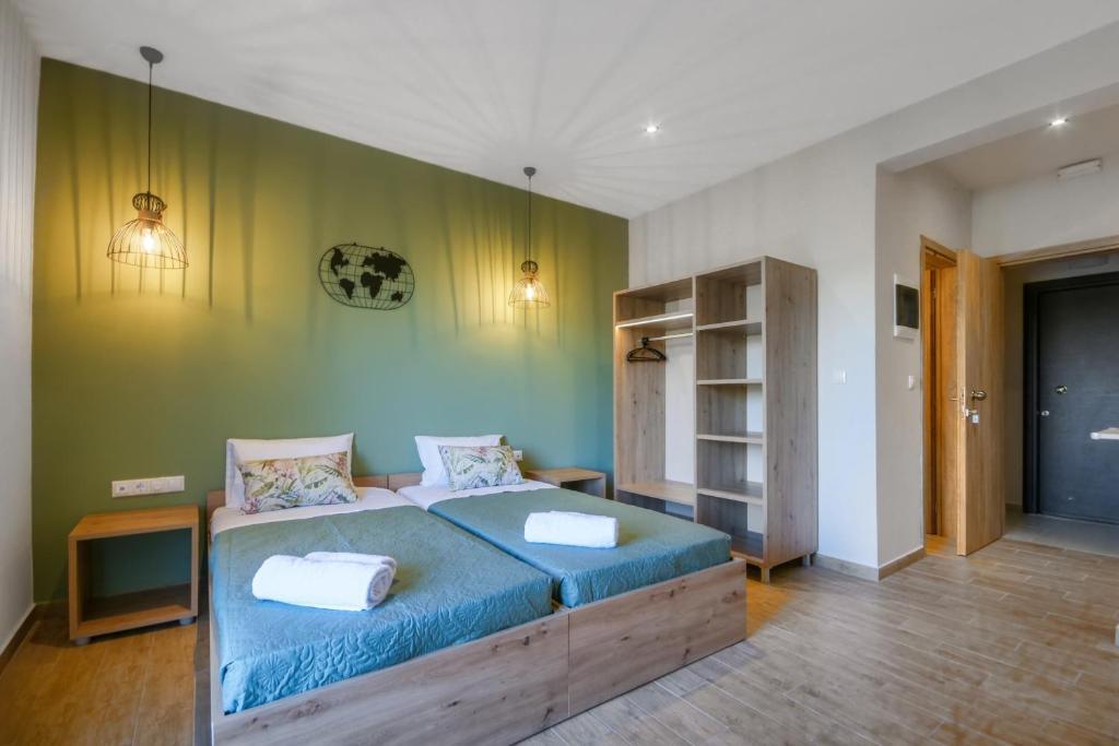 a bedroom with a bed with blue sheets and a green wall at Ariadni Apartments Dassia in Dassia