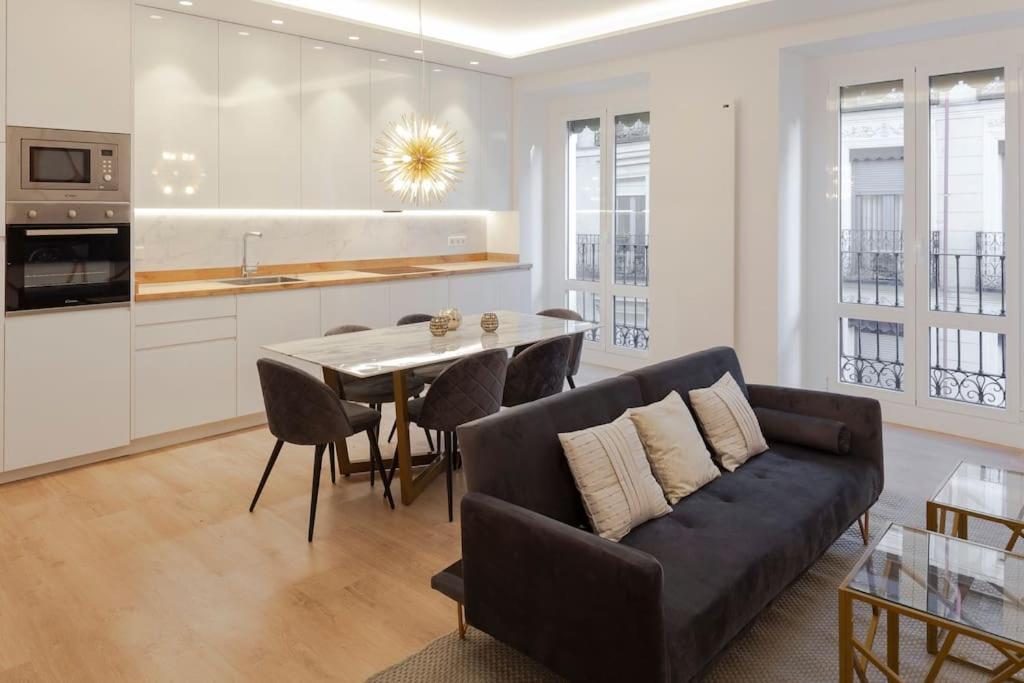 ein Wohnzimmer mit einem Sofa und einem Tisch mit Stühlen in der Unterkunft Luxury flat Chamberi II in Madrid