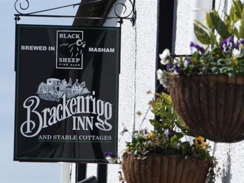 a black and white sign on a building with plants at Brackenrigg Inn in Watermillock