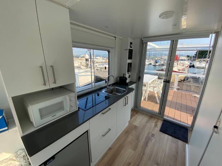 cocina con fregadero, microondas y ventana en Casa flotante con terraza en un marco inigualable, en Ribadeo