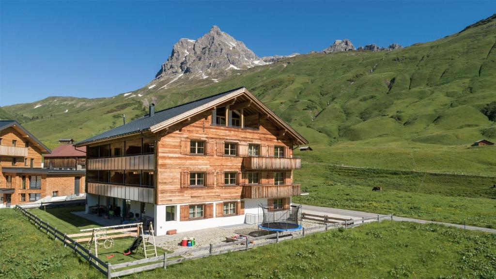 ein Holzhaus mit einem Berg im Hintergrund in der Unterkunft Alphus Appartements in Warth am Arlberg