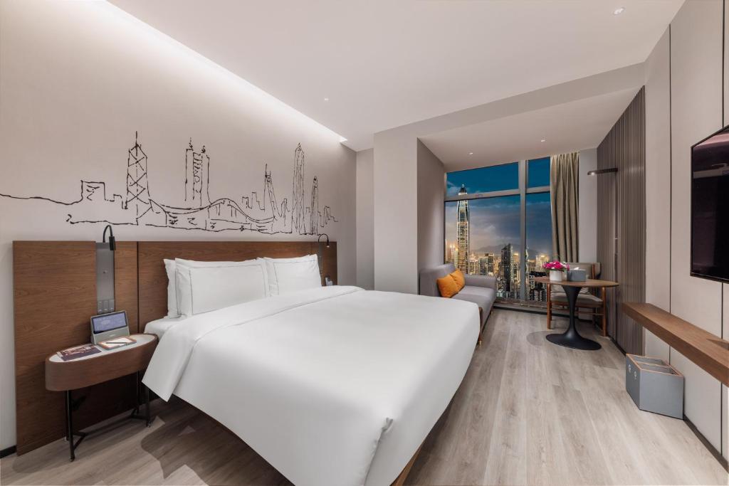 a hotel room with a large white bed and a window at UrCove By Hyatt ShenZhen Bay in Shenzhen