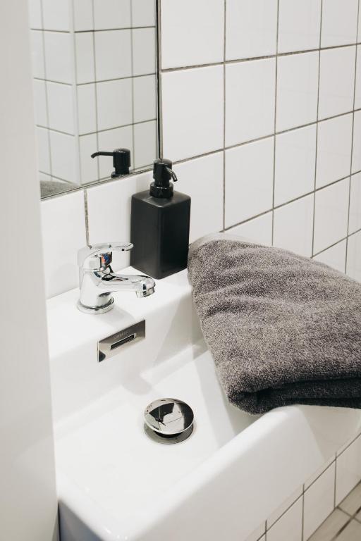 Small white sink with chrome faucet, black soap dispenser and gray folded towel.