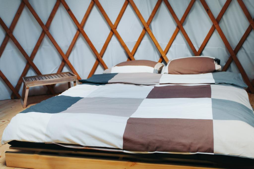 Double bed with patchwork duvet inside yurt, wooden lattice walls and small side bench.
