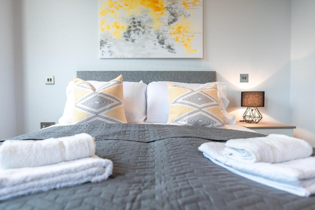 a bedroom with a large bed with towels on it at Apartment Nine Staines Upon Thames - Free Parking - Heathrow - Thorpe Park in Staines
