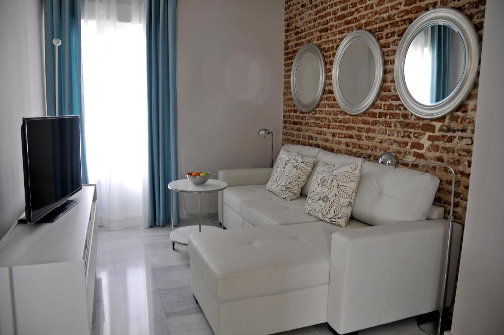 メリダにあるRSI Apartamentosの白いソファとレンガの壁が備わるリビングルーム
