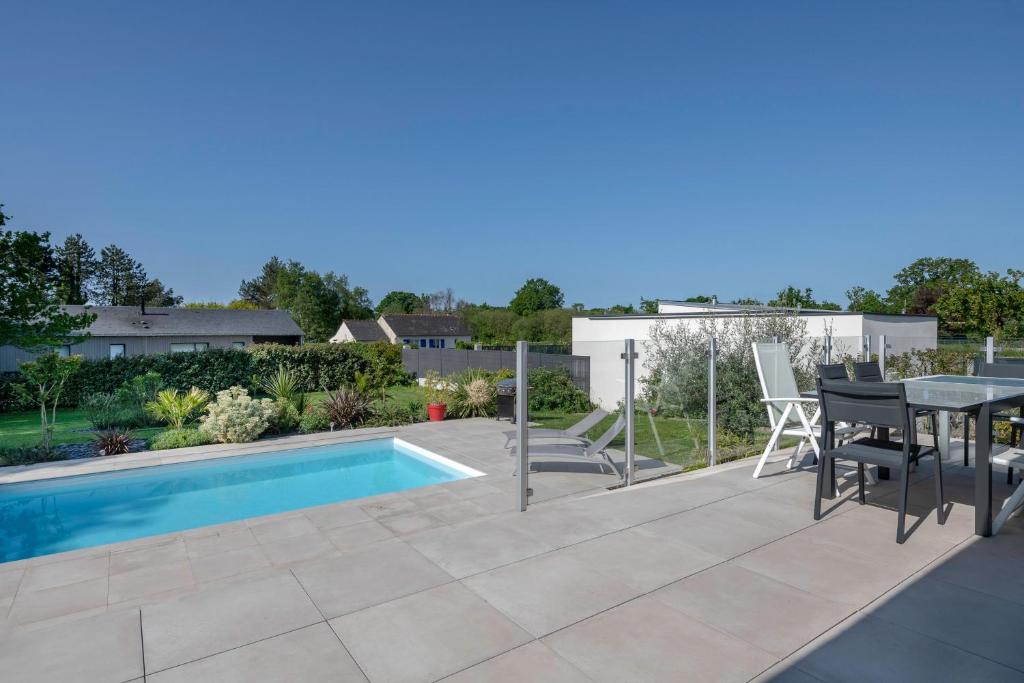 a patio with a table and chairs next to a swimming pool at Deconnexion et detente sur la Presqu ile de Rhuys in Le Tour-du-Parc