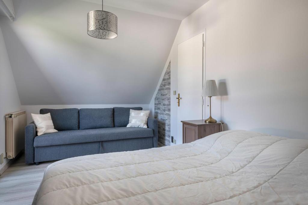 a bedroom with a bed and a blue couch at Deconnexion et detente sur la Presqu ile de Rhuys in Le Tour-du-Parc