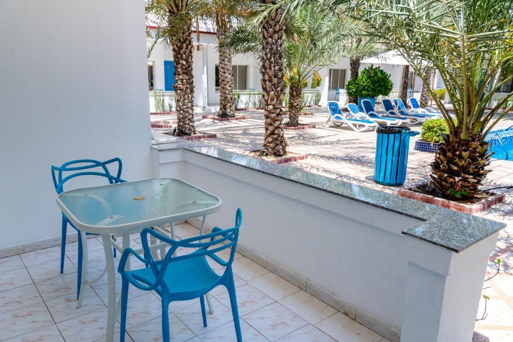 a table and chairs on a balcony with palm trees at Fujairah Hotel & Resort in Fujairah