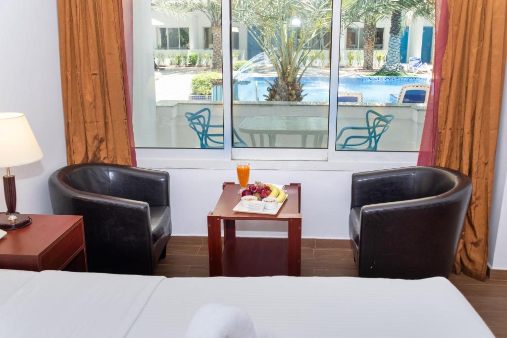 a hotel room with two chairs and a table and a bed at Fujairah Hotel & Resort in Fujairah