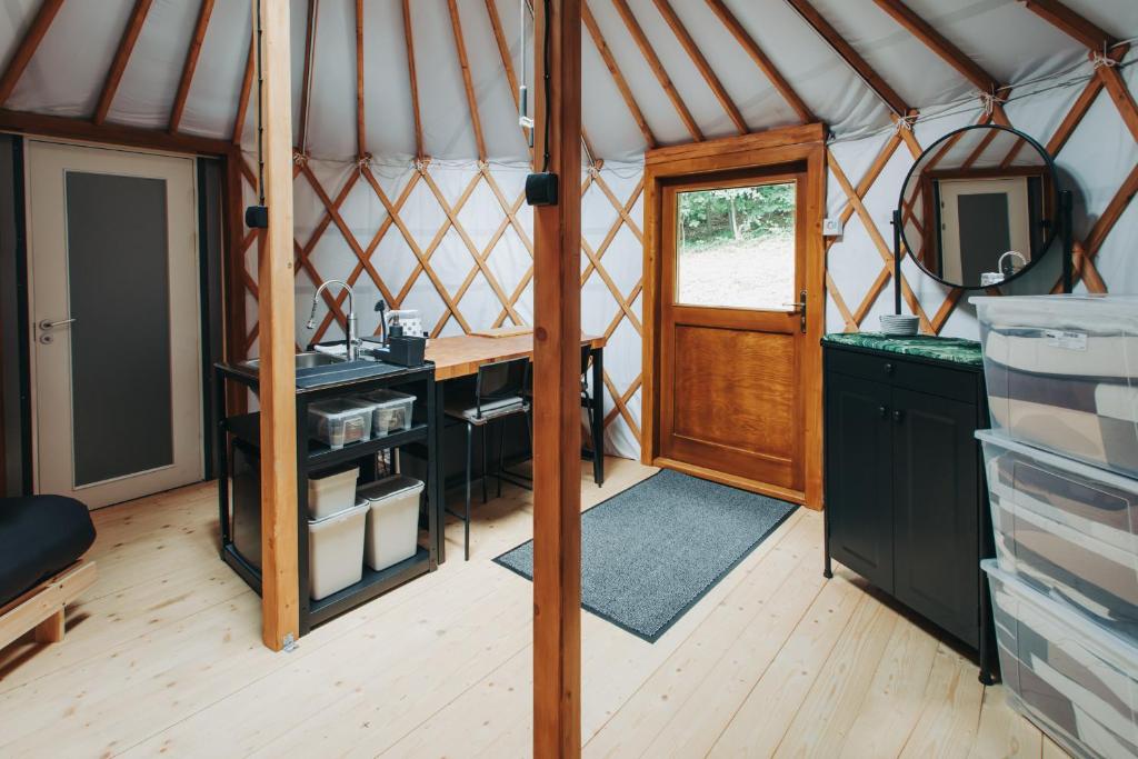 Yurt interior showing wooden door, kitchenette island, dining bar and storage drawers.