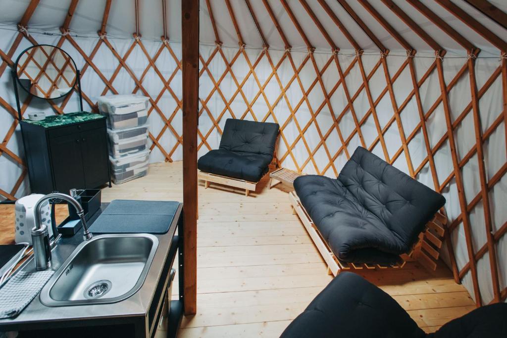 Interior of yurt with low black futons, wooden lattice walls and compact kitchenette.