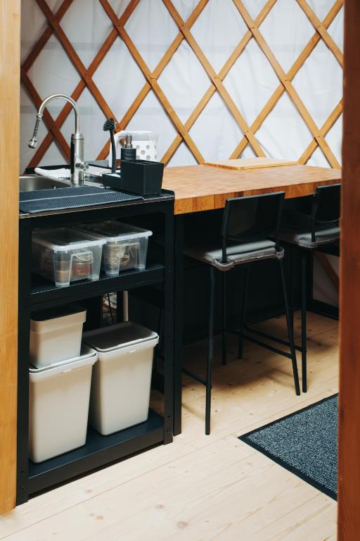 Compact sink station with open shelving, storage bins and two high stools at bar.