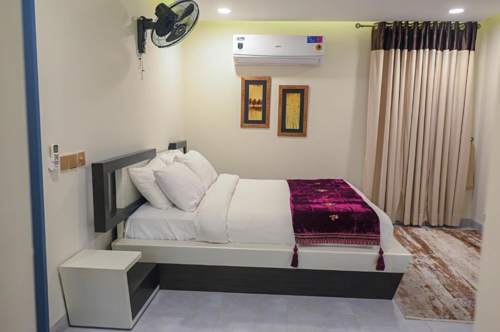 a bedroom with a bed with white sheets and pillows at The Luxus Lodge in Islamabad