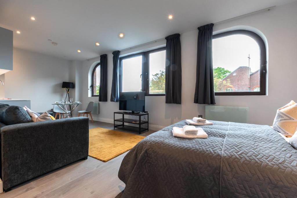 a bedroom with a bed and a couch and windows at Apartment Twenty Three Staines Upon Thames - Free Parking - Heathrow - Thorpe Park in Staines