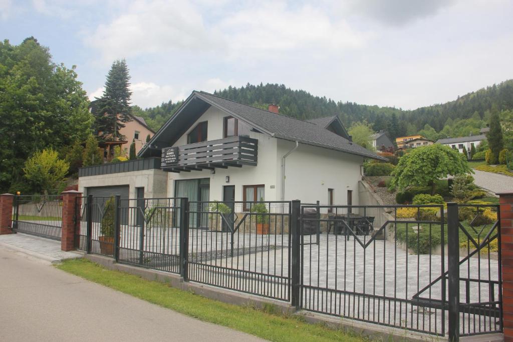 ein weißes Haus mit einem schwarzen Zaun in der Unterkunft Domek nad Żylicą in Szczyrk