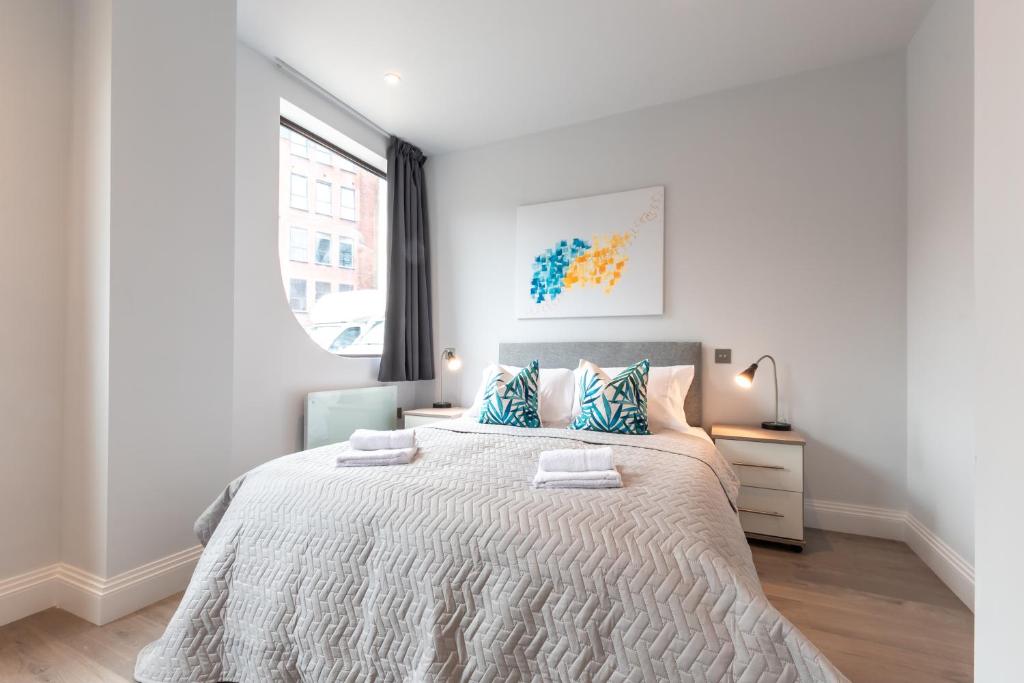 um quarto branco com uma cama grande e almofadas azuis em Apartment Thirty Five Staines Upon Thames - Free Parking - Heathrow - Thorpe Park em Staines
