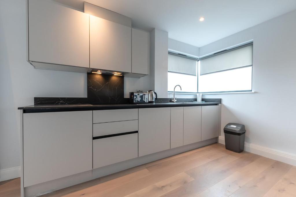 a kitchen with white cabinets and a sink at Apartment Forty Staines Upon Thames - Free Parking - Heathrow - Thorpe Park in Staines