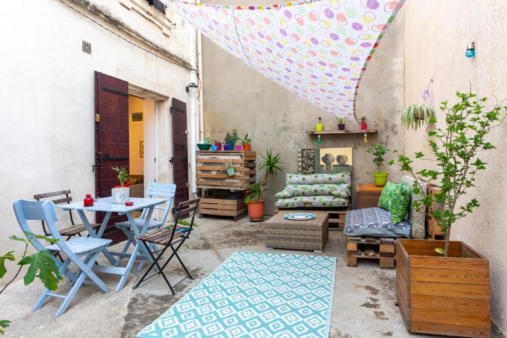 un patio avec une table, des chaises et un parasol dans l'établissement L'Observance - Au cœur du centre historique, à Arles