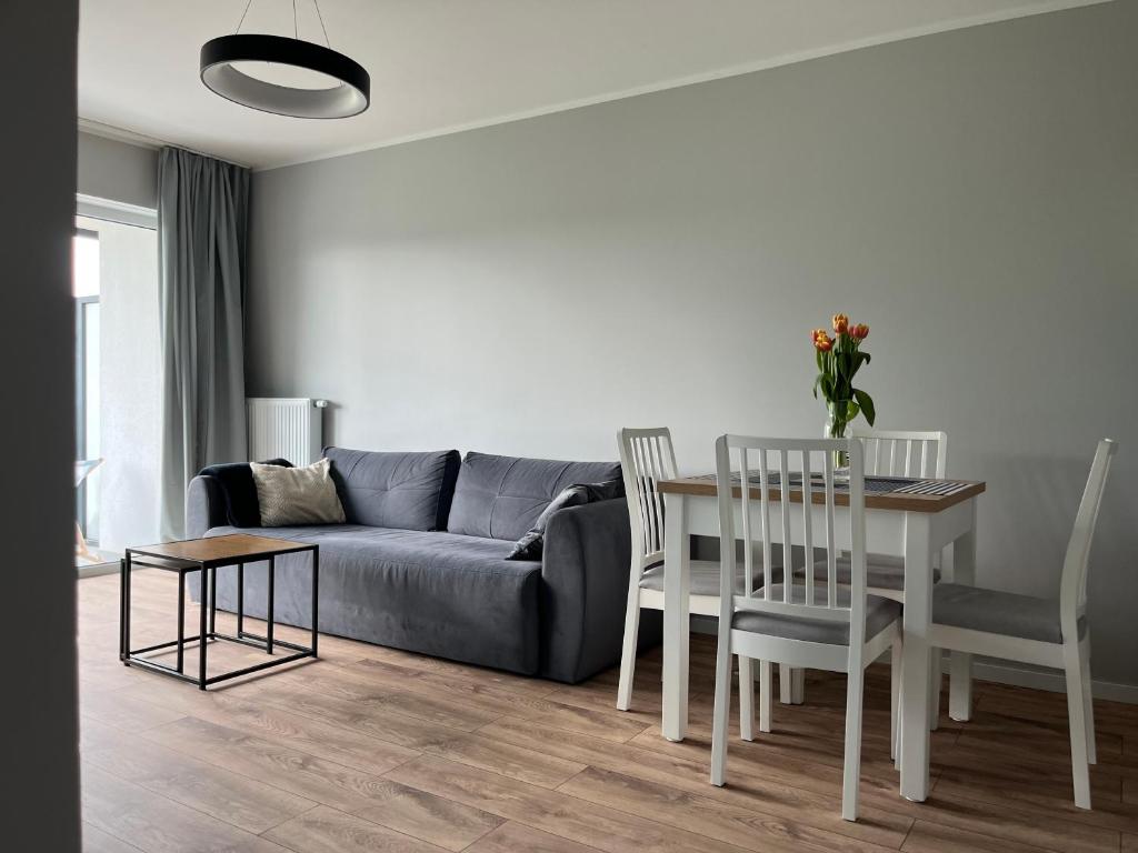 a living room with a couch and a table and chairs at Apartament Porta Mare Dziwnów in Dziwnów