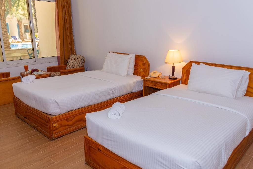 a bedroom with two beds and a table with a lamp at Fujairah Hotel & Resort in Fujairah