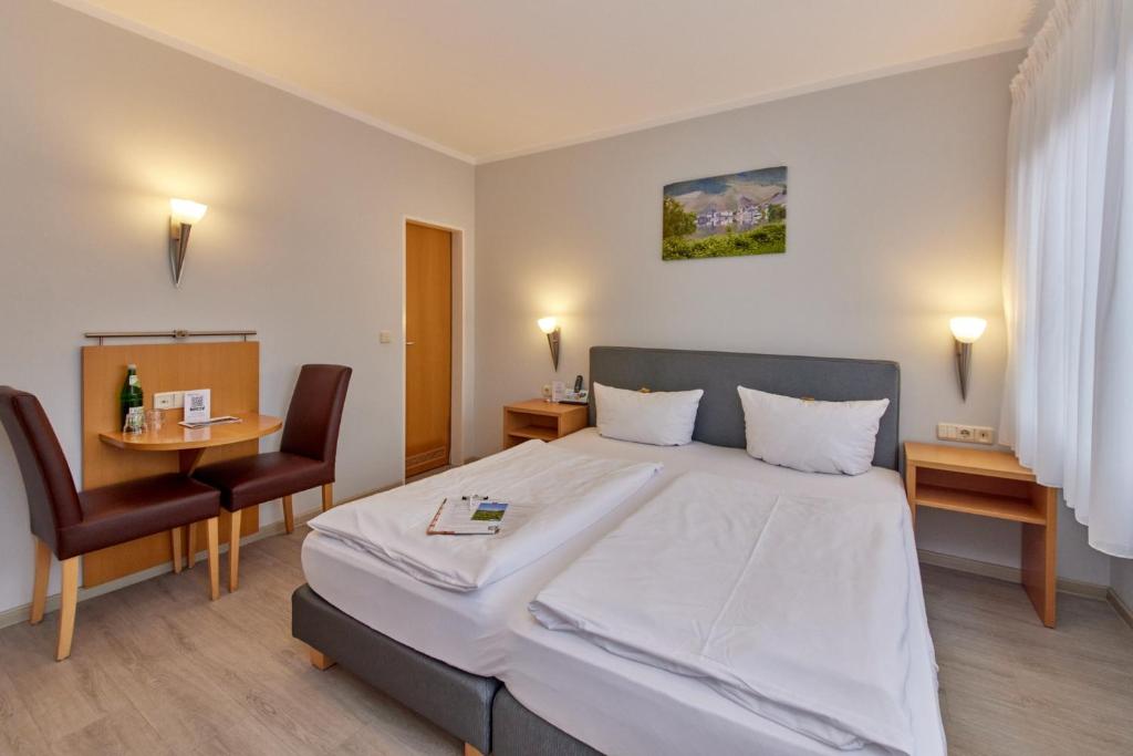 a bedroom with a large bed and a table and chairs at Moselhaus Weiskopf `SelfCheckIn`OffSiteBreakfast`CityParking` in Bernkastel-Kues
