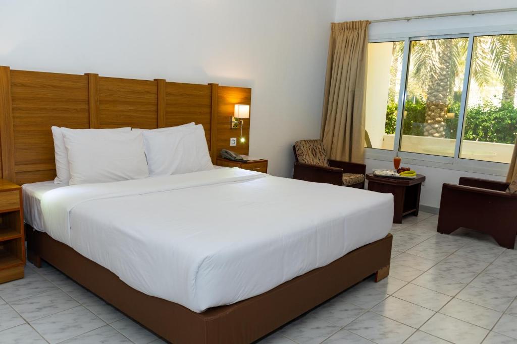 a bedroom with a large white bed and a window at Fujairah Hotel & Resort in Fujairah