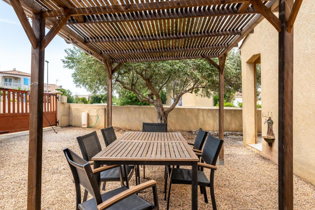 a wooden table and chairs under a wooden pergola at La Villa d'Isa et Seb in Narbonne