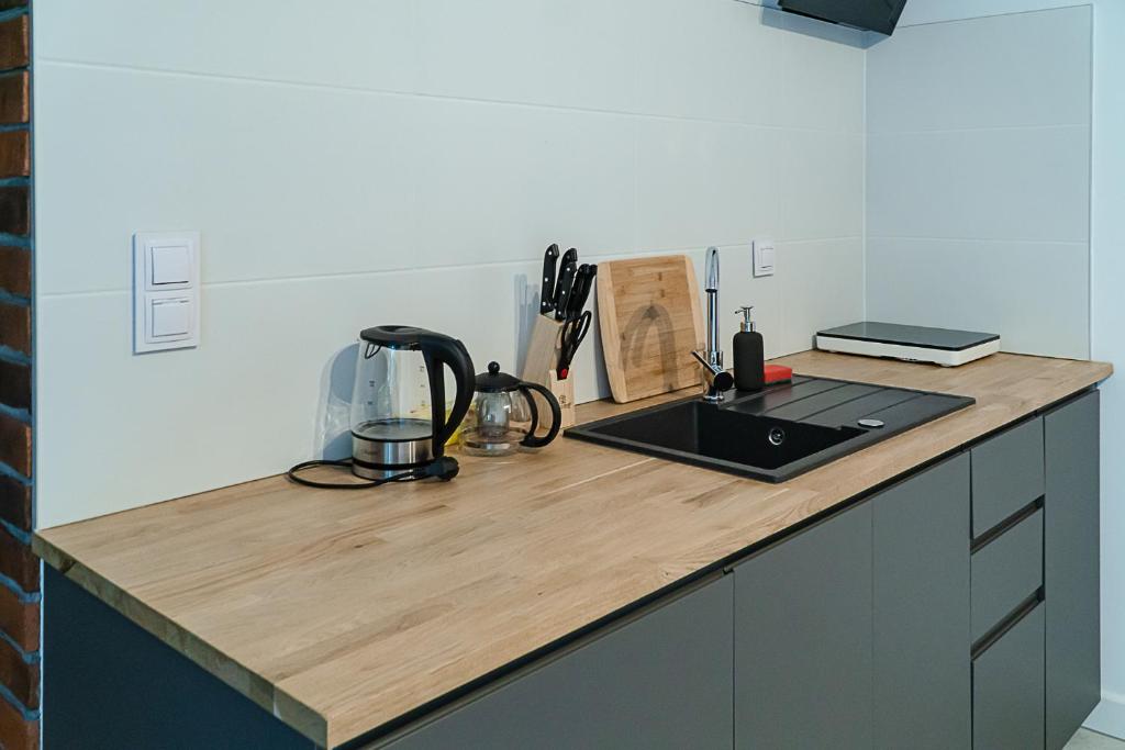 Wooden kitchenette counter with sink, electric kettle, knife block and cutting board.