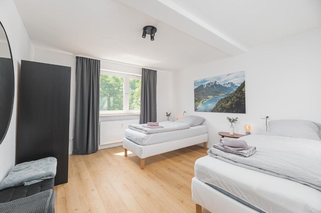 a white bedroom with two beds and a window at Moderne Ferienwohnung in Lorch in Lorch