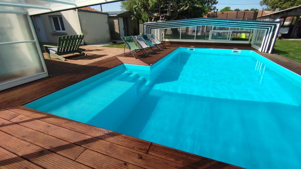 una gran piscina azul en una terraza de madera en Le Making Of Chambres d'Hôtes insolites et Familiales, en Thairé