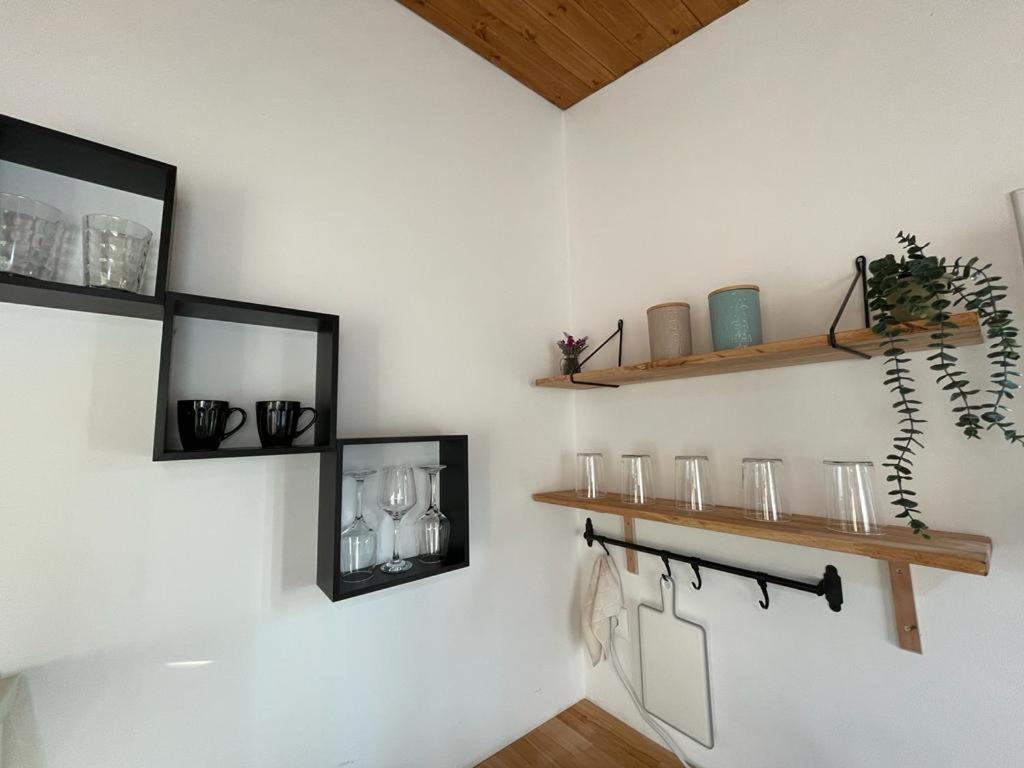 a white wall with shelves and glasses on it at Cozy Wooden House in Durrës