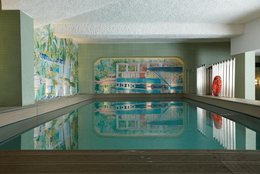 a swimming pool in a building with a painting on the wall at Drawing House in Paris