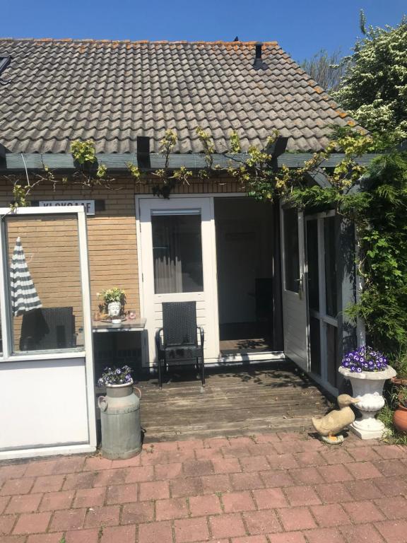 a patio of a house with a door and a chair at Bed & Breakfast Klokgaaf in De Koog