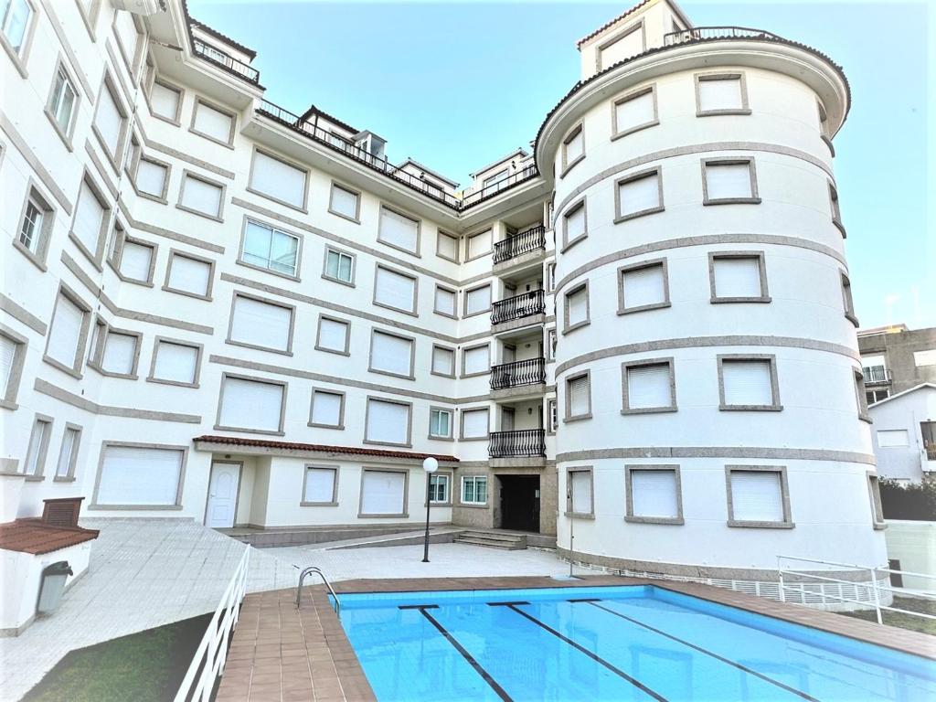 an apartment building with a swimming pool in front of it at Apartamento Welcome Grañamar in Sanxenxo