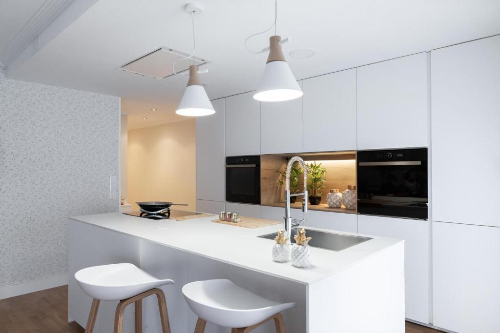 a kitchen with white cabinets and white stools at Home Luxury - Villagarcía in Vilagarcia de Arousa