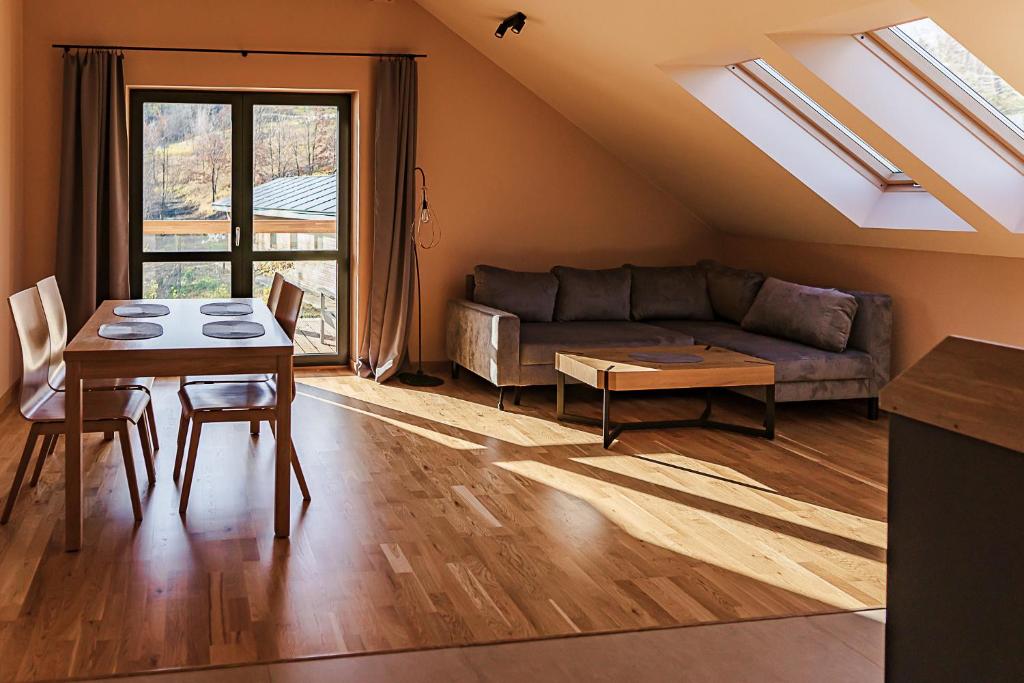Sunlit living room with dining table by glass doors, L-shaped sofa and skylights.