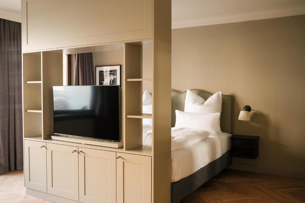 a bedroom with a tv and a bed with white pillows at Mimosa Hotel in Westerland (Sylt)