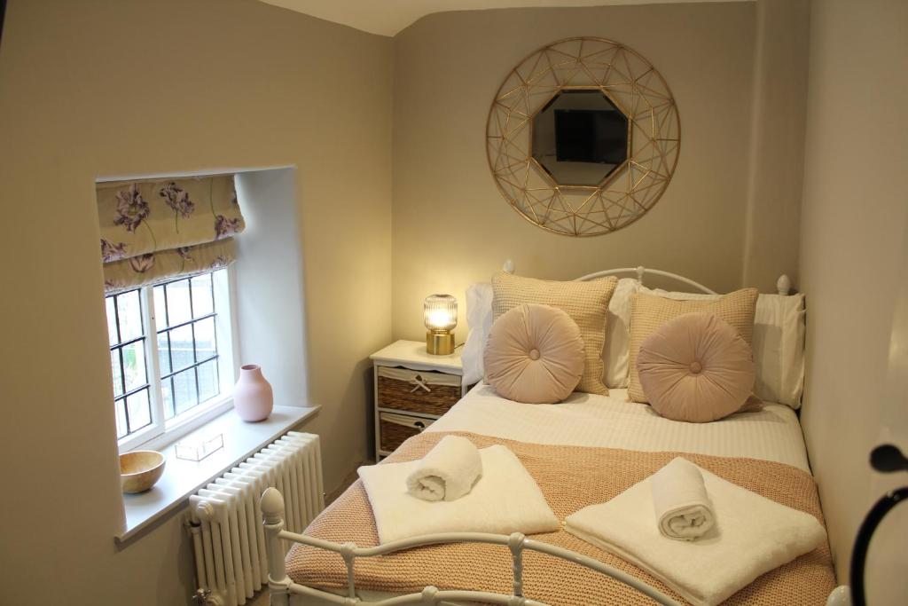um quarto com uma cama com almofadas e um espelho em The Nook em Bakewell