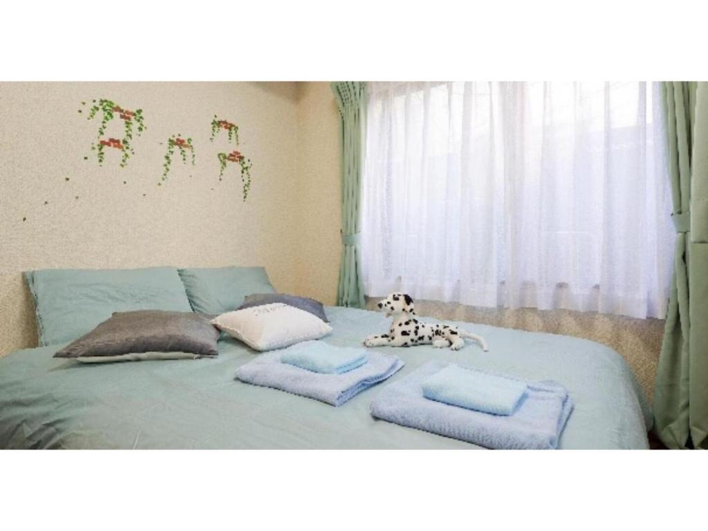 łóżko z poduszkami i pies siedzący na nim w obiekcie Cosmo Mercy N-1 / Vacation STAY 12990 w Tokio