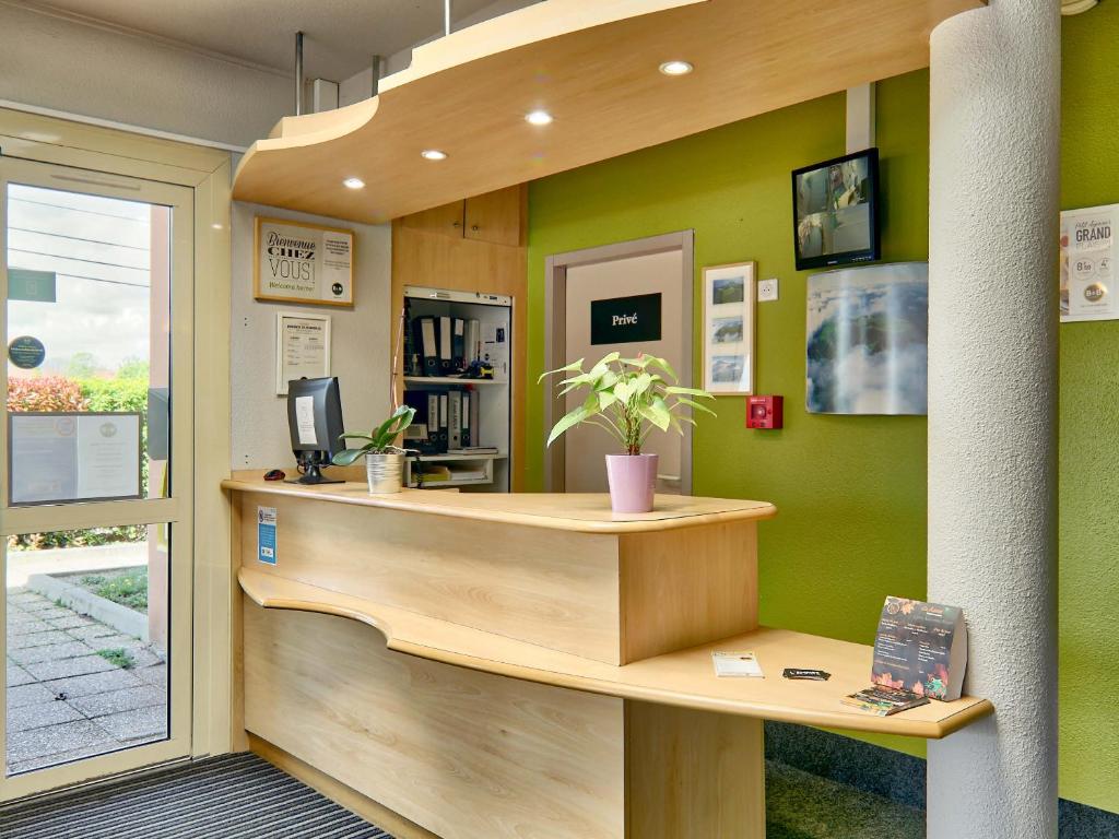 a reception desk in a office with green walls at B&B HOTEL Clermont-Ferrand Gerzat in Gerzat