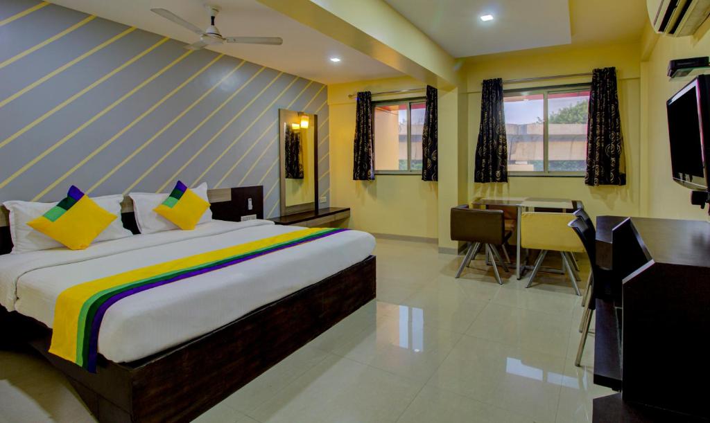 a bedroom with a bed and a desk and a kitchen at Itsy By Treebo - Prince Regency in Pune